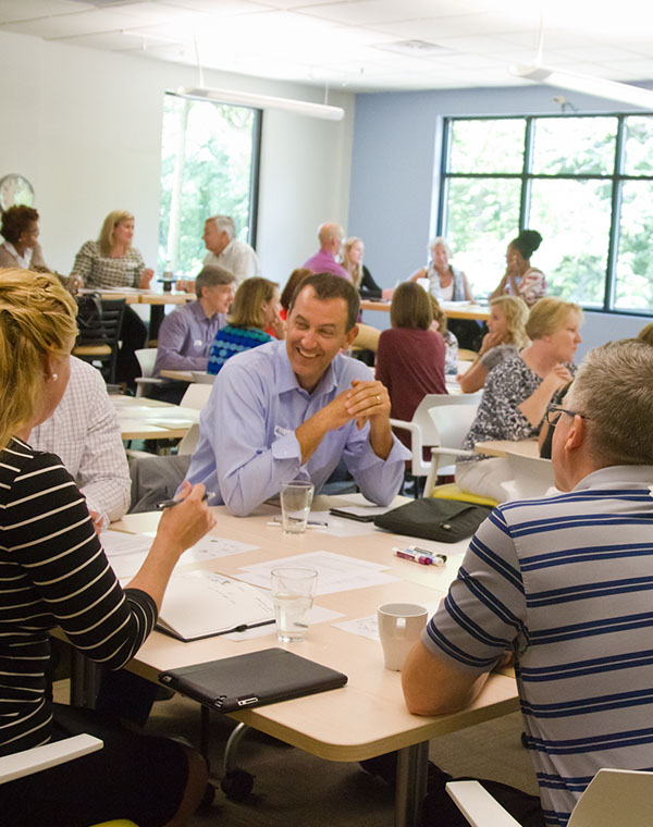 Man smiling, sitting at a table at a Thought design team development training.